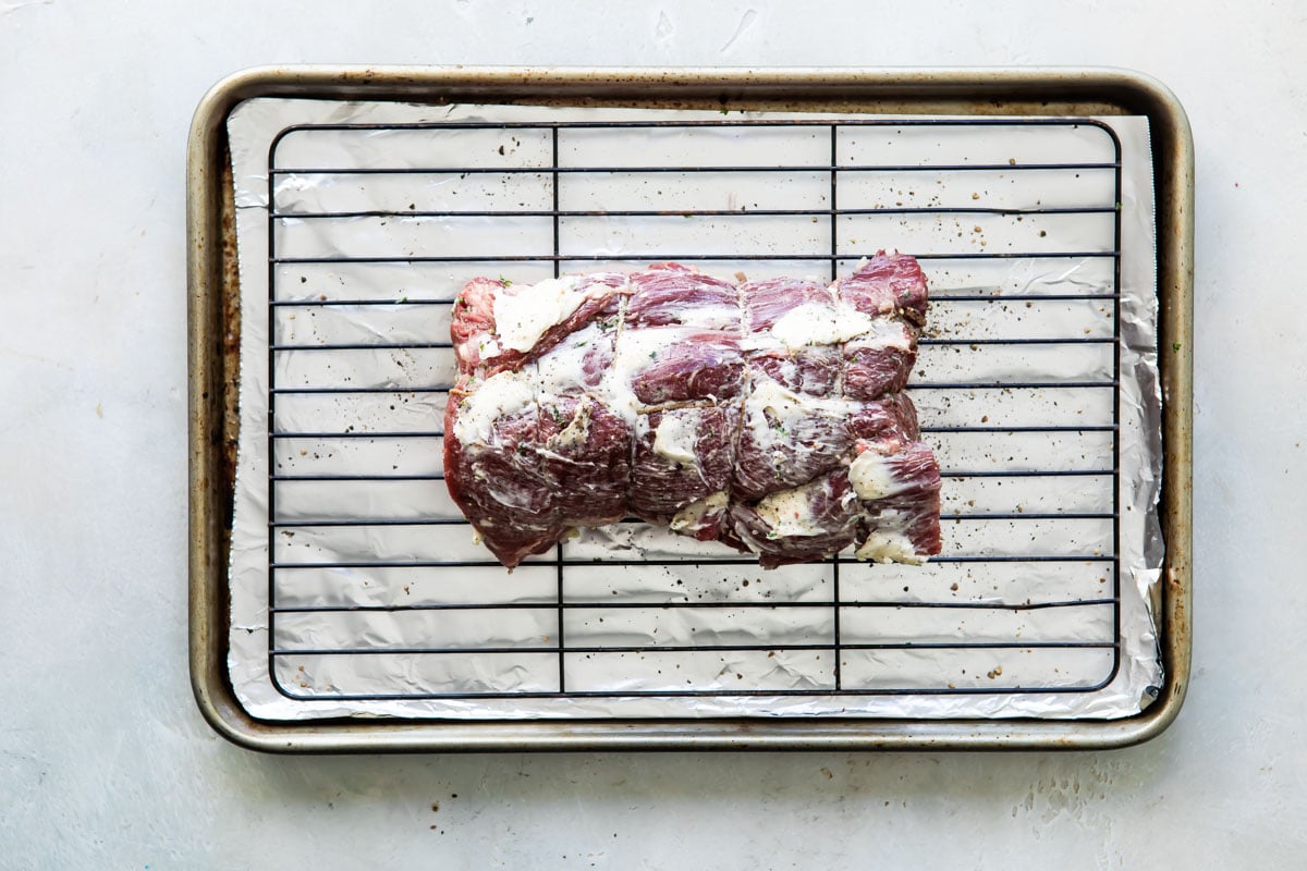 A tied beef tenderloin on a rack rubbed with shallot parsley butter.