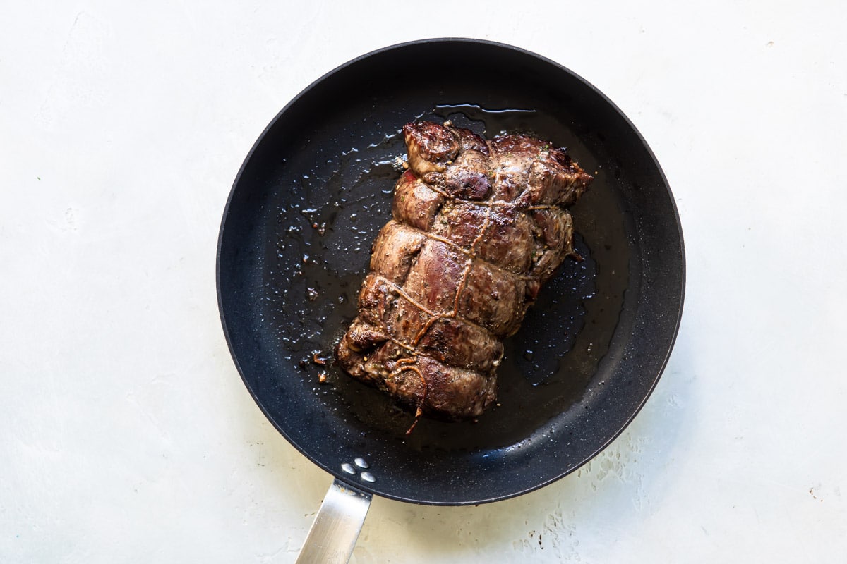 Browning a beef tenderloin in a skillet.