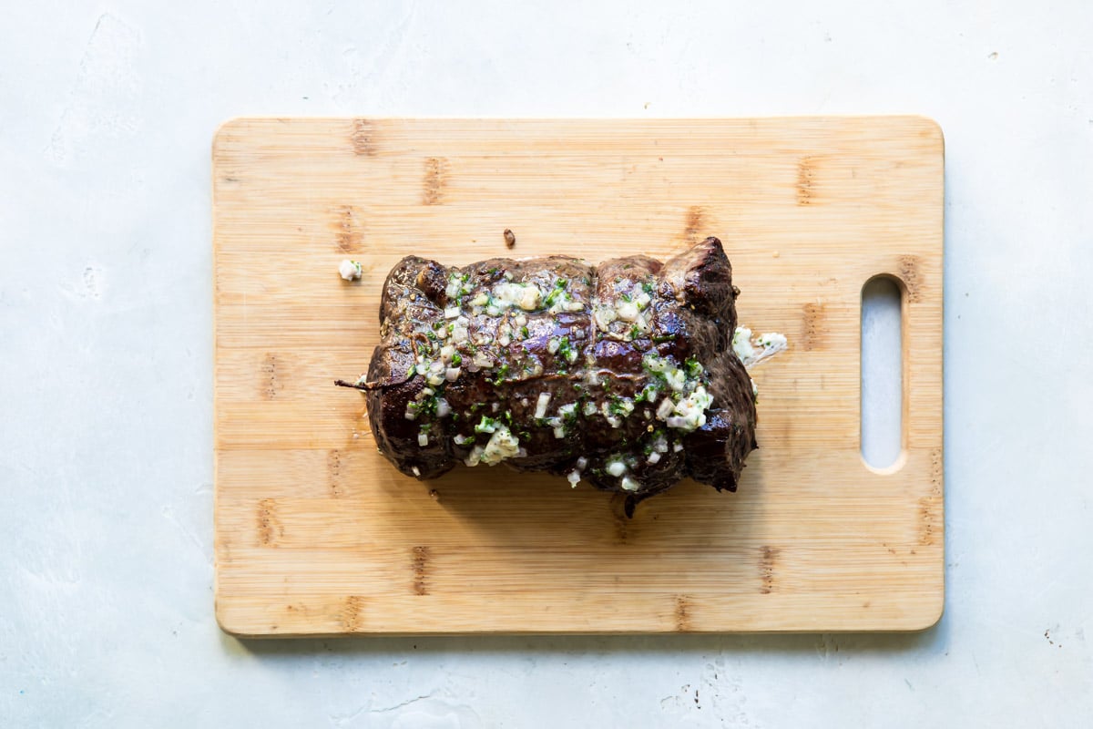 Rubbing shallot butter on a roasted beef tenderloin.