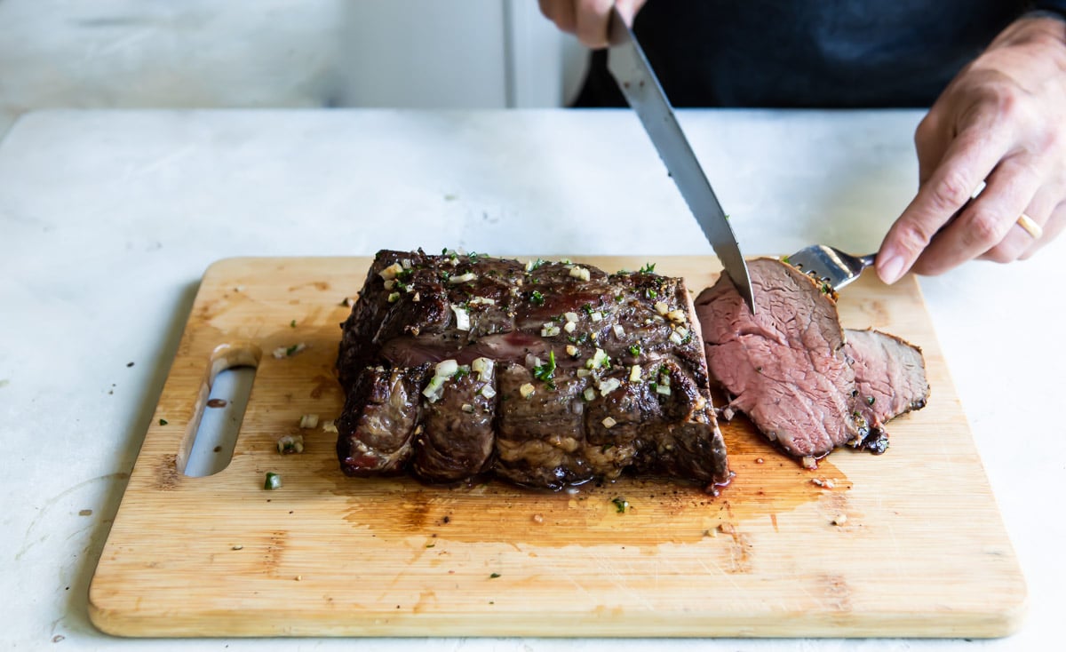 Rubbing shallot butter on a roasted beef tenderloin.