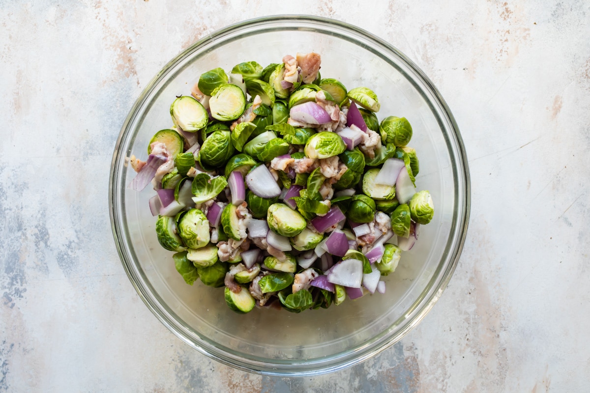 A bowl of Brussels sprouts, red onion, and bacon.