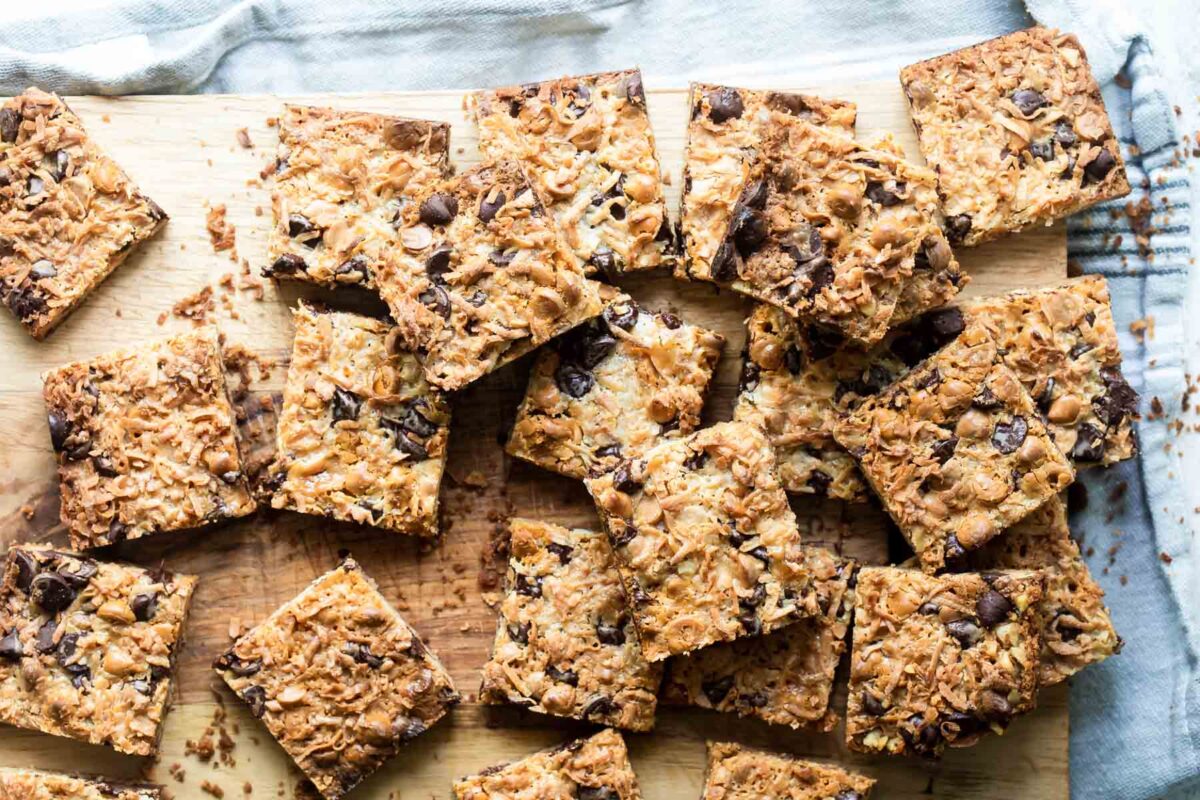 Seven layer bars squares on a wooden cutting board.