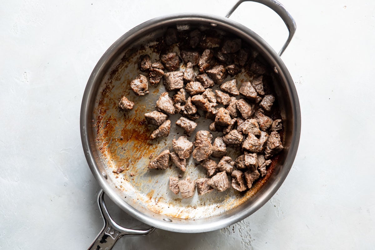Pieces of beef in a skillet for beef barley soup.