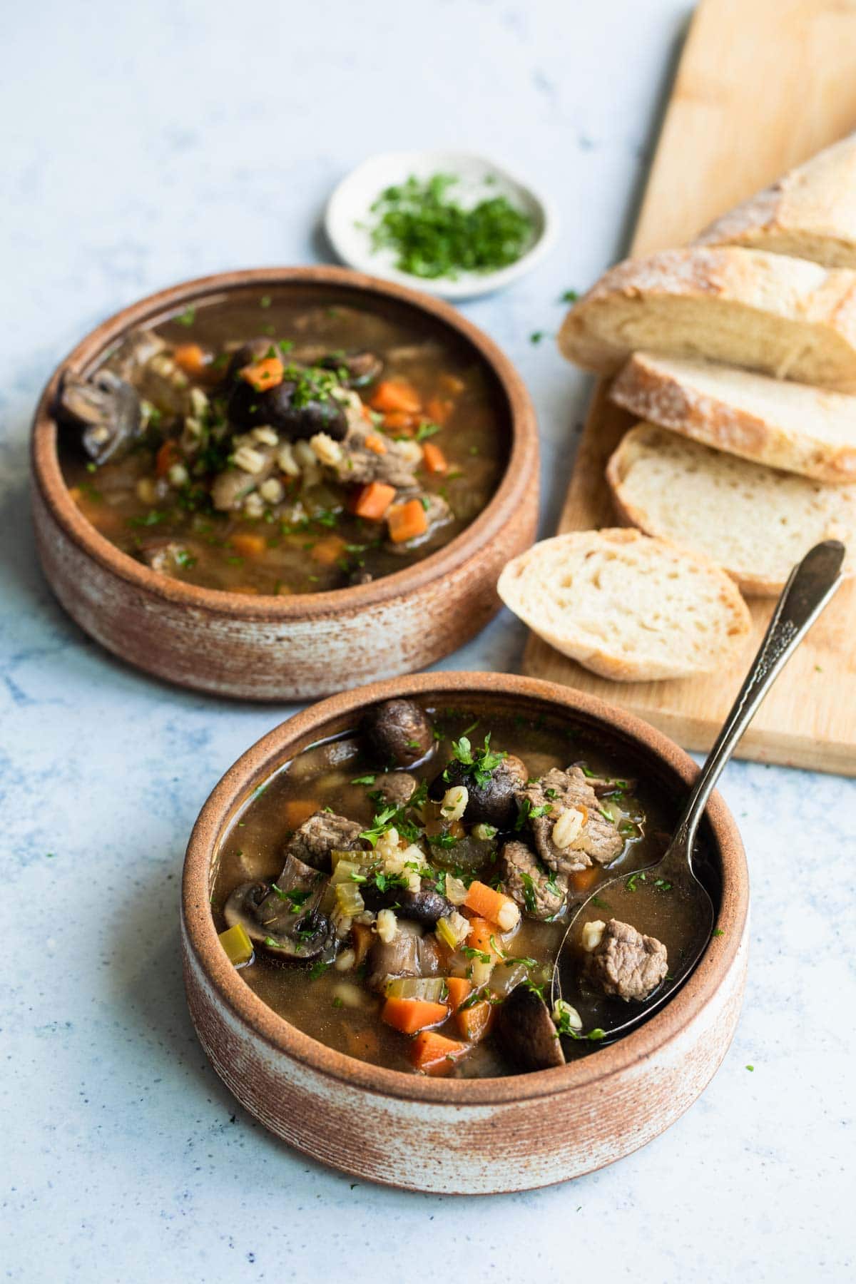 Slow cooker beef barley soup in two bowls.