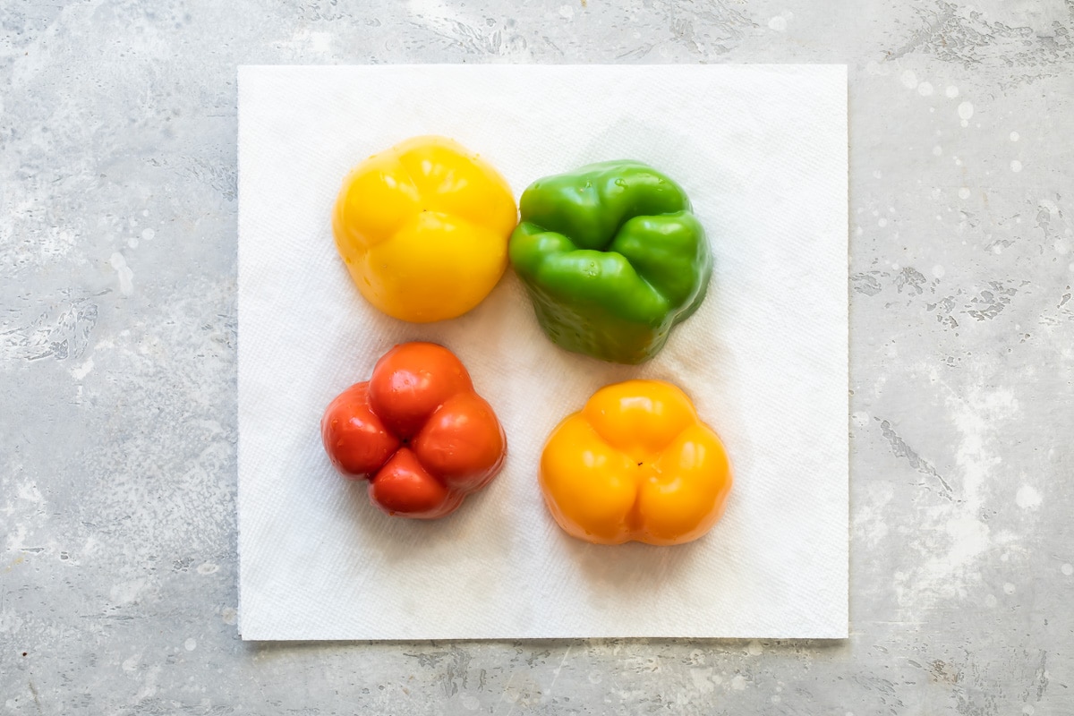 Four bell peppers on a white paper towel.