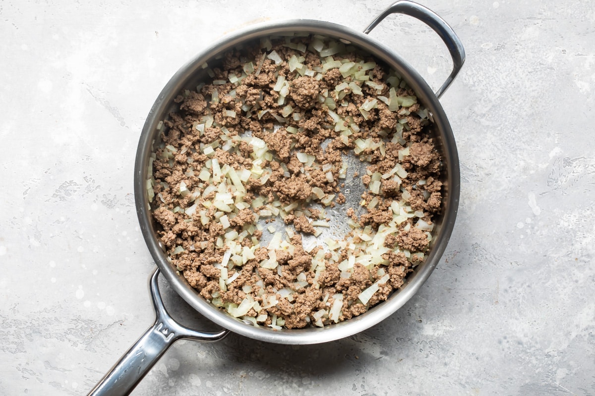 A skillet with cooked ground beef and onion.