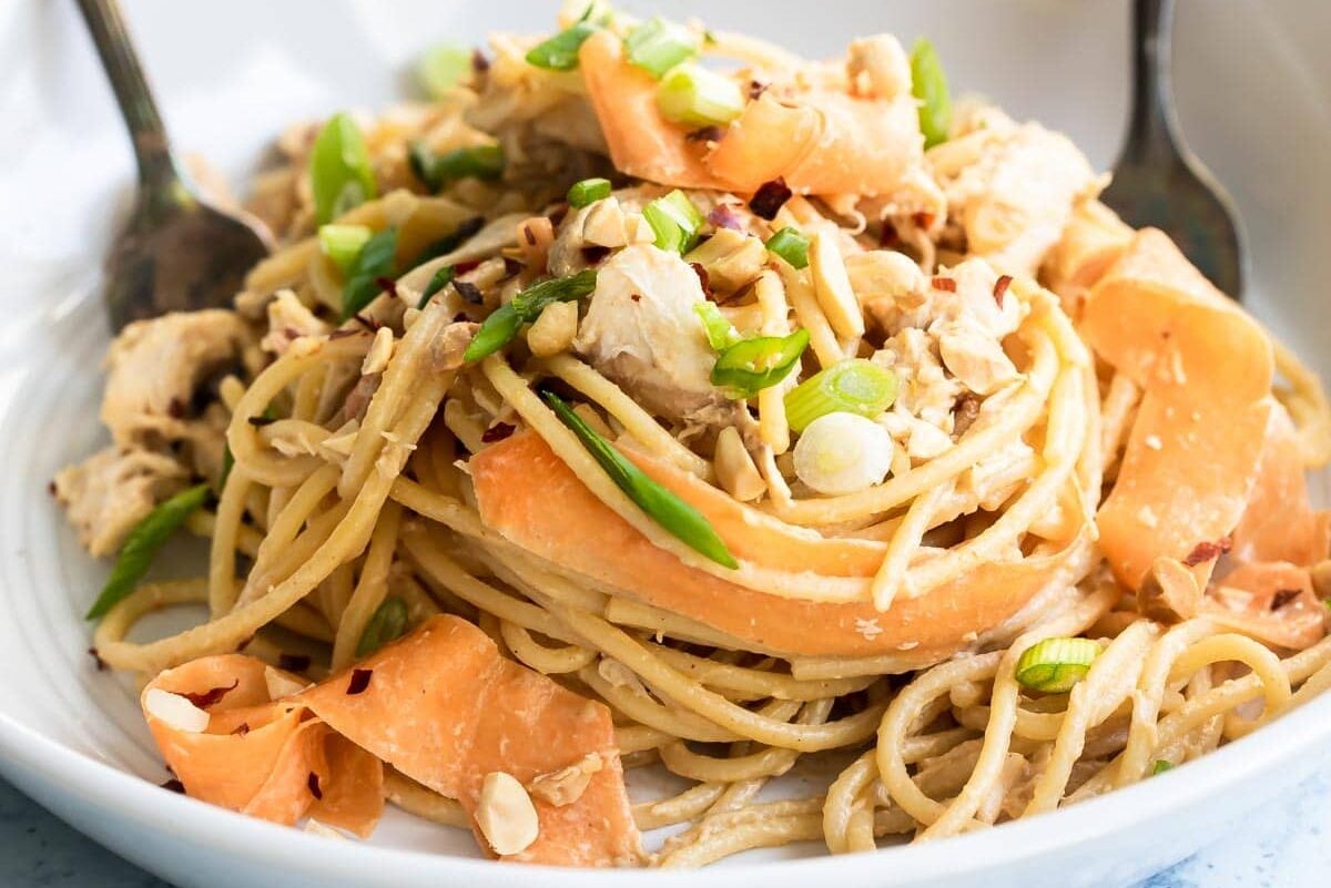 Thai peanut chicken noodles in a white bowl.
