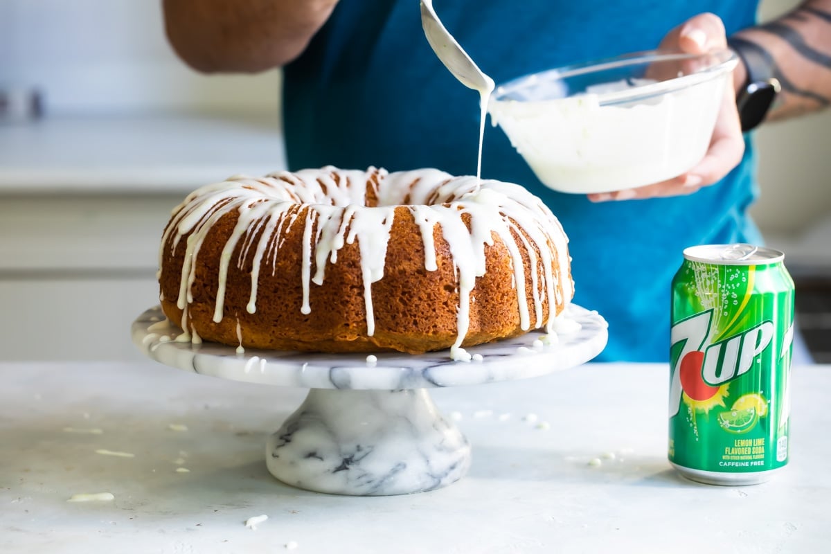 Someone drizzling glaze over a 7 up cake.
