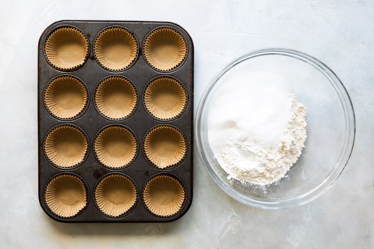 Dry ingredients for blueberry muffins next to a muffin tin.