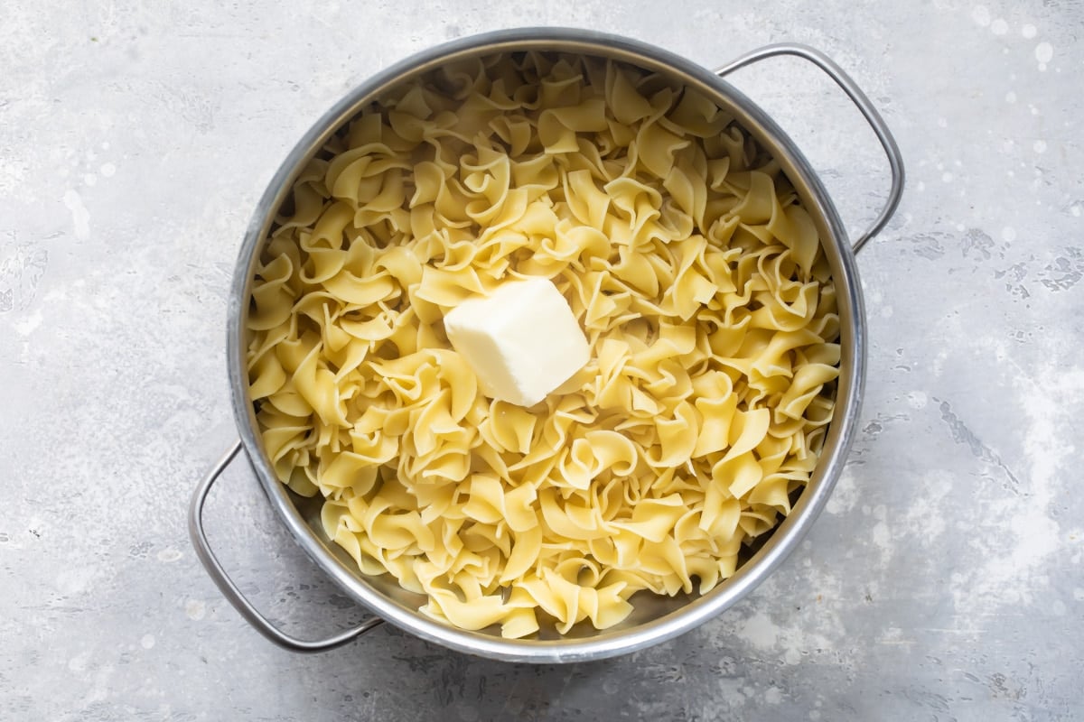 Buttered noodles in a sliver pot.