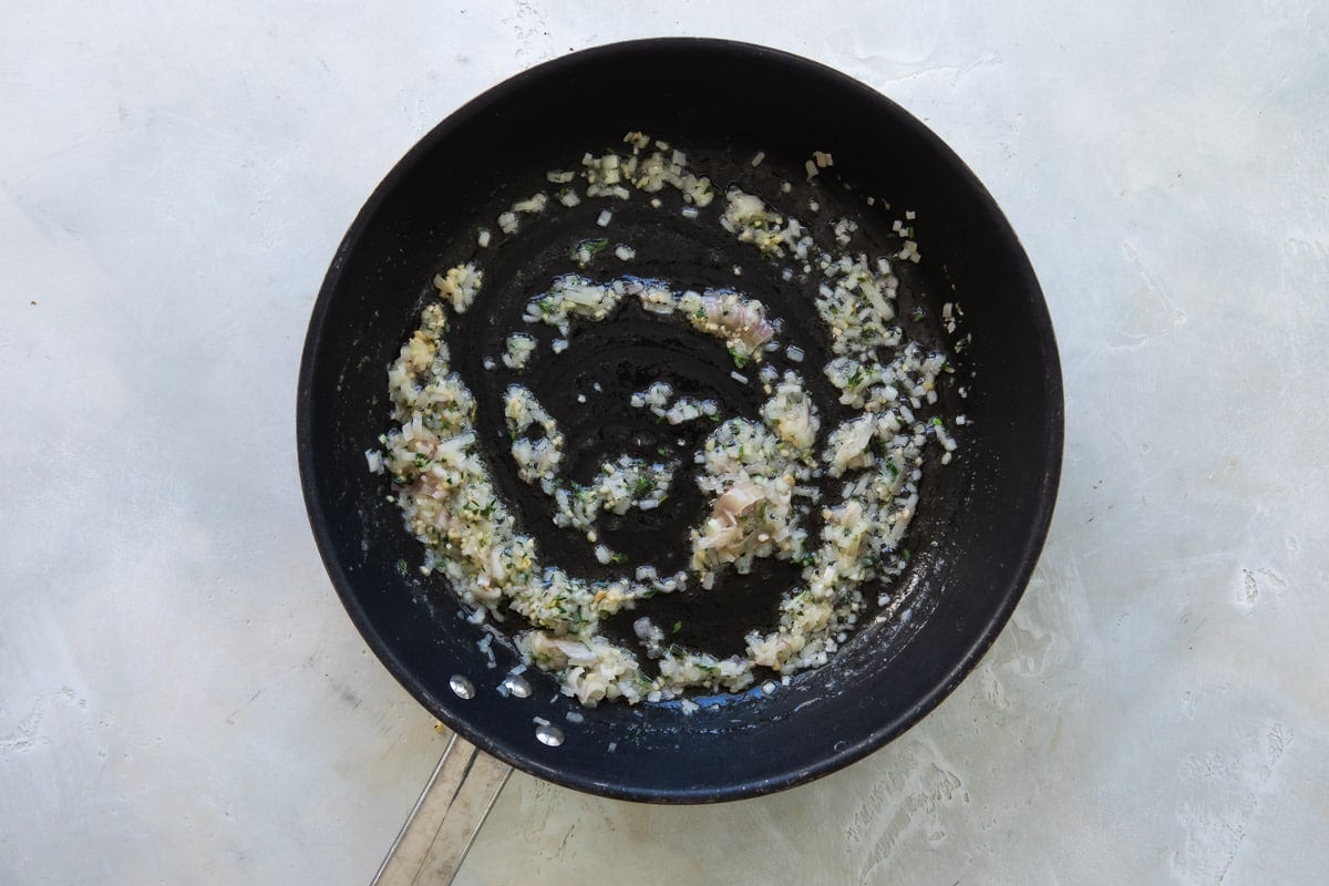Garlic, oil and spices in a black skillet.