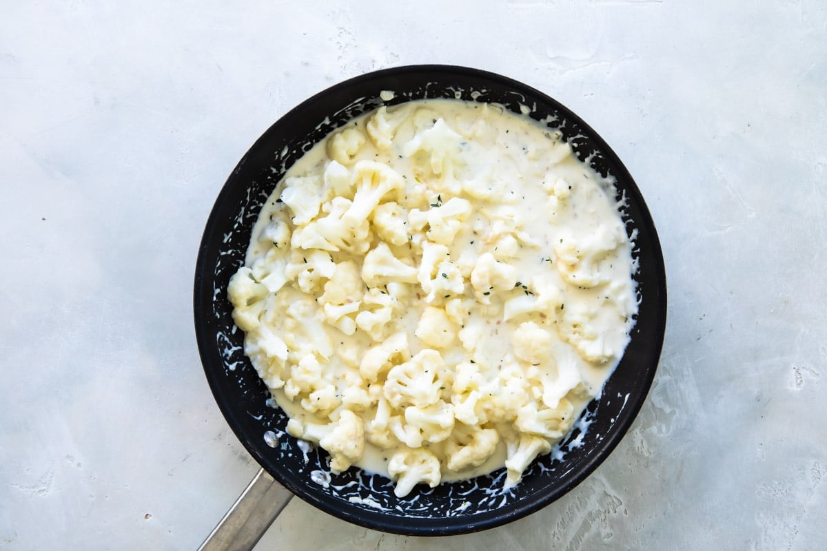 Cauliflower gratin in a black skillet.