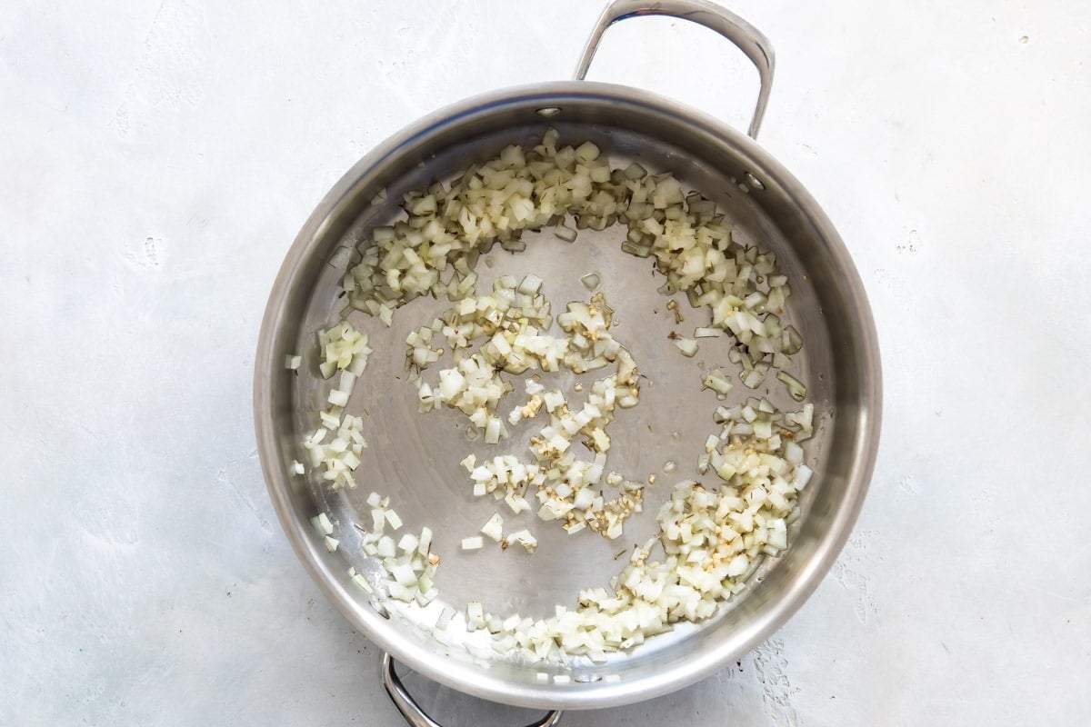 Garlic and onion being sautéed in a skillet.