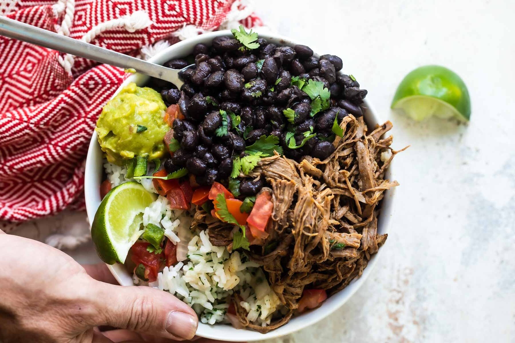 A bowl of Chipotle copycat Barbacoa beef with black beans, cilantro-lime rice, and pico de gallo salsa.