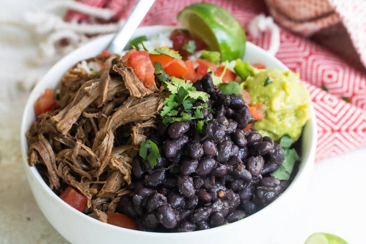 A bowl of Chipotle copycat Barbacoa beef with black beans, cilantro-lime rice, and pico de gallo salsa.