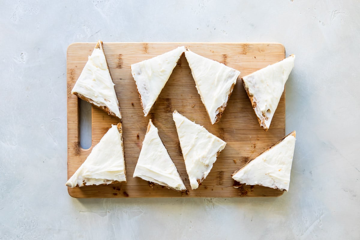 Cranberry bliss bar triangles on a wooden cutting board.