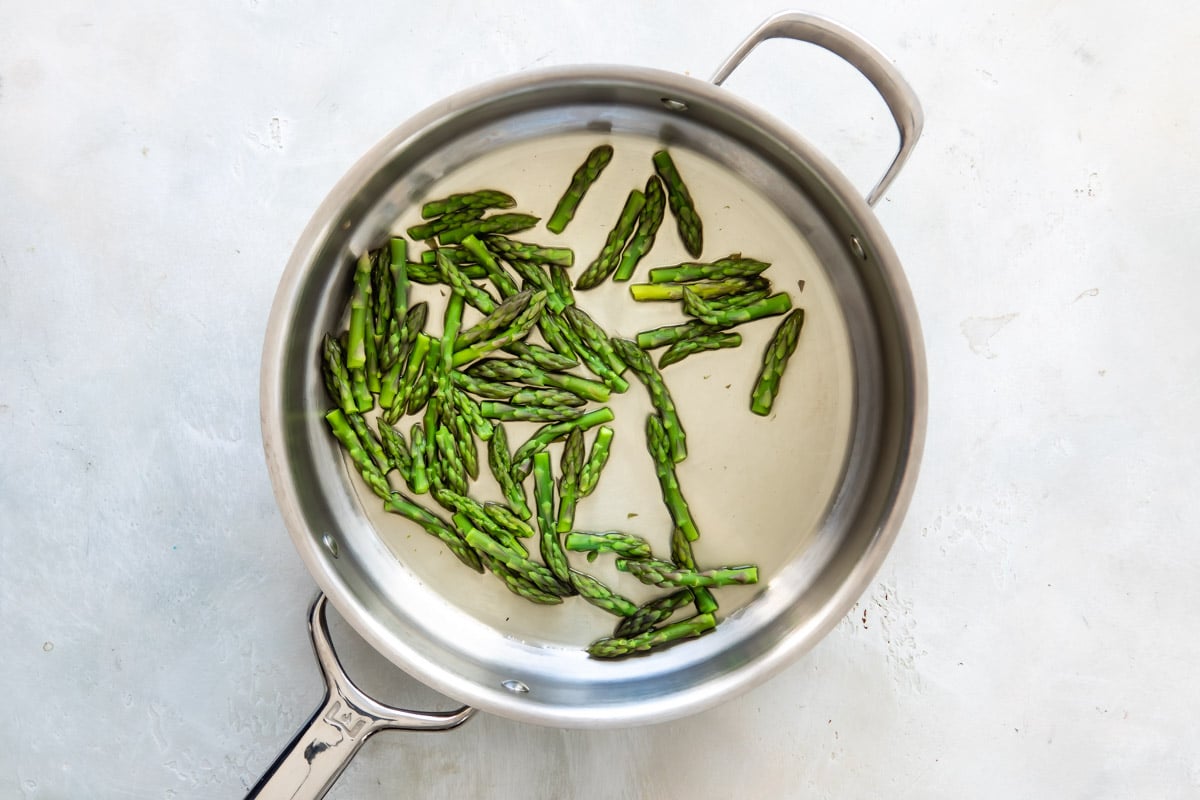 Sauteeing asparagus tips in a skillet.