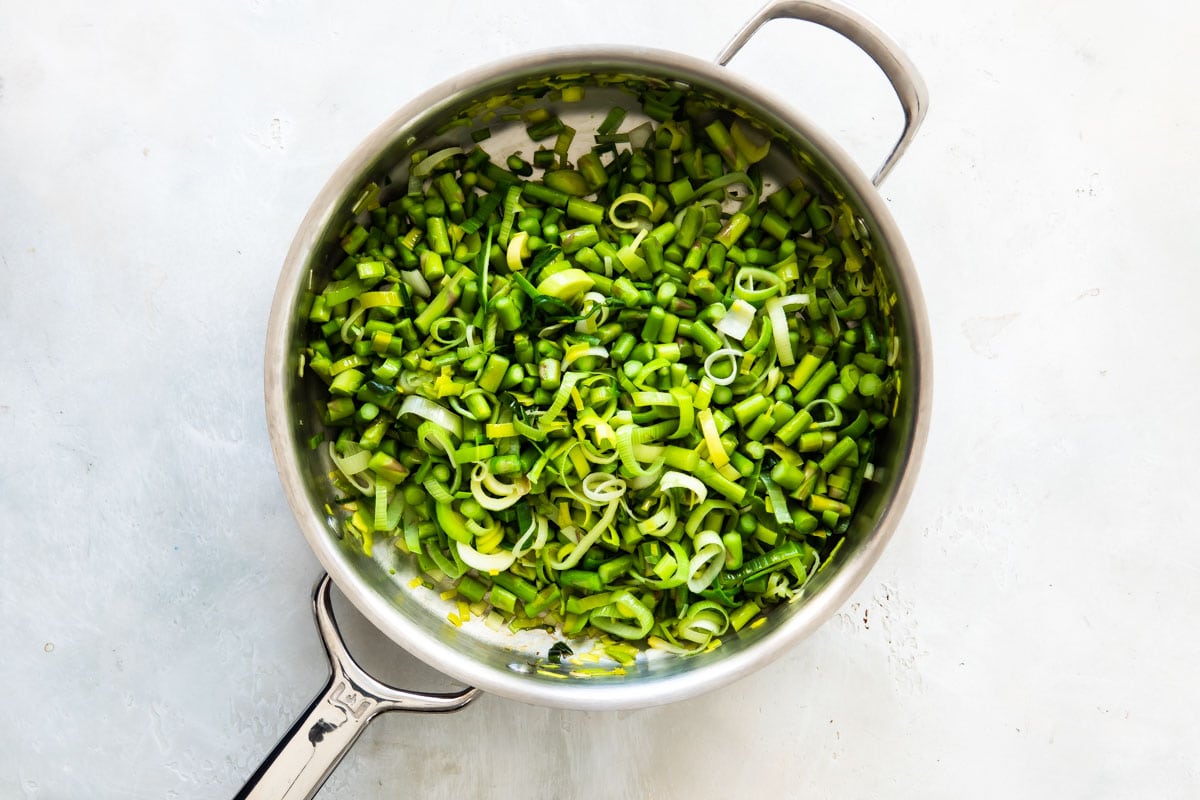 Cooking leeks and asparagus in a skillet.