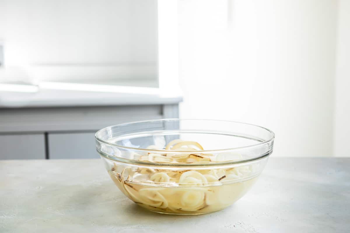 Spiralized potatoes in a bowl of water.
