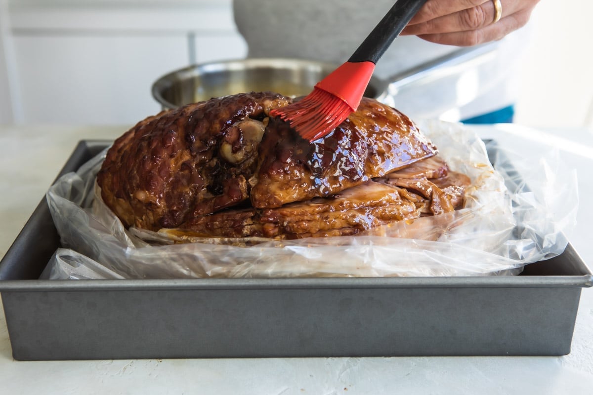 Someone glazing a ham.