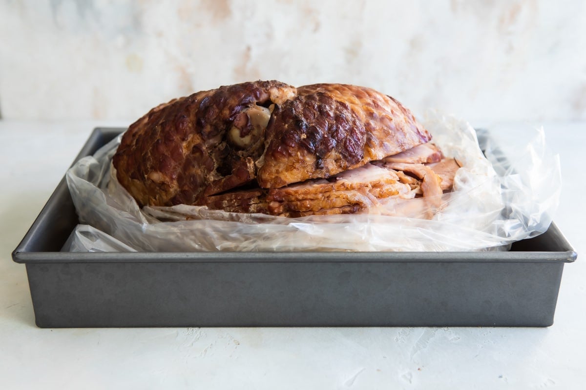 A ham in a bag resting in a roasting pan.