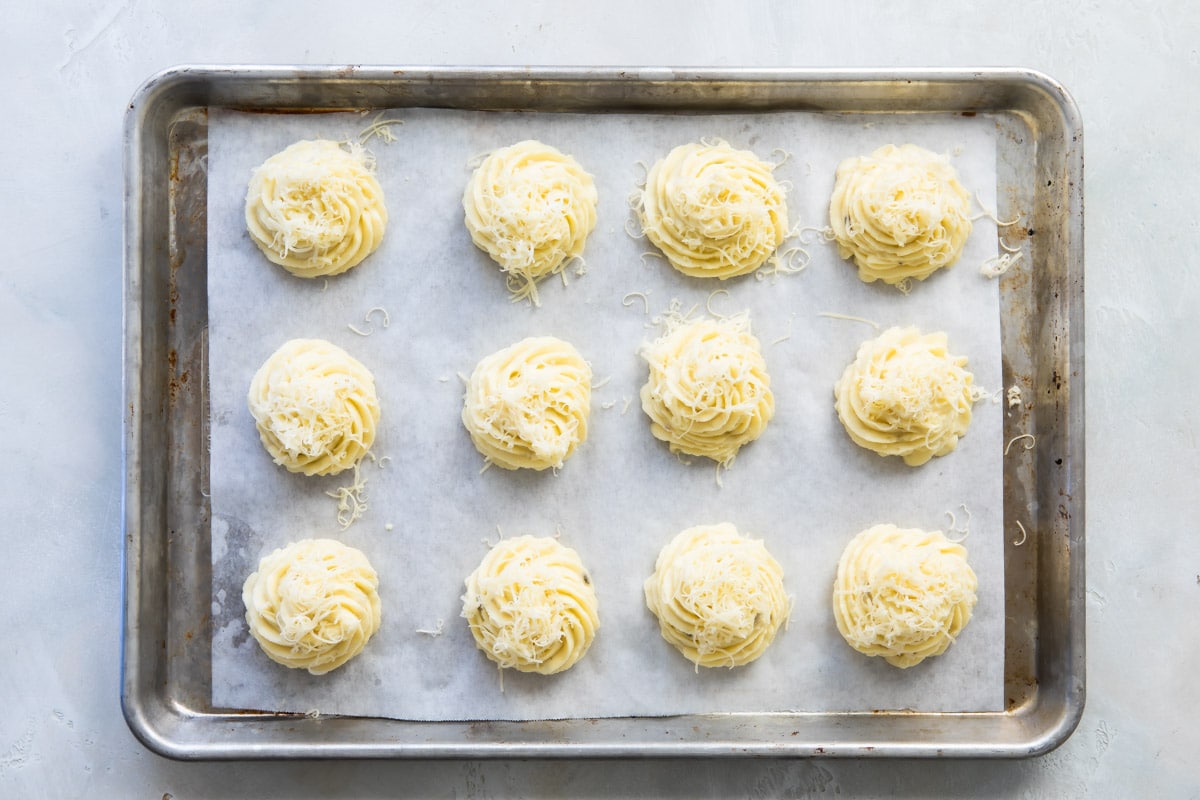 A baking sheet with Duchess potatoes piped on top.