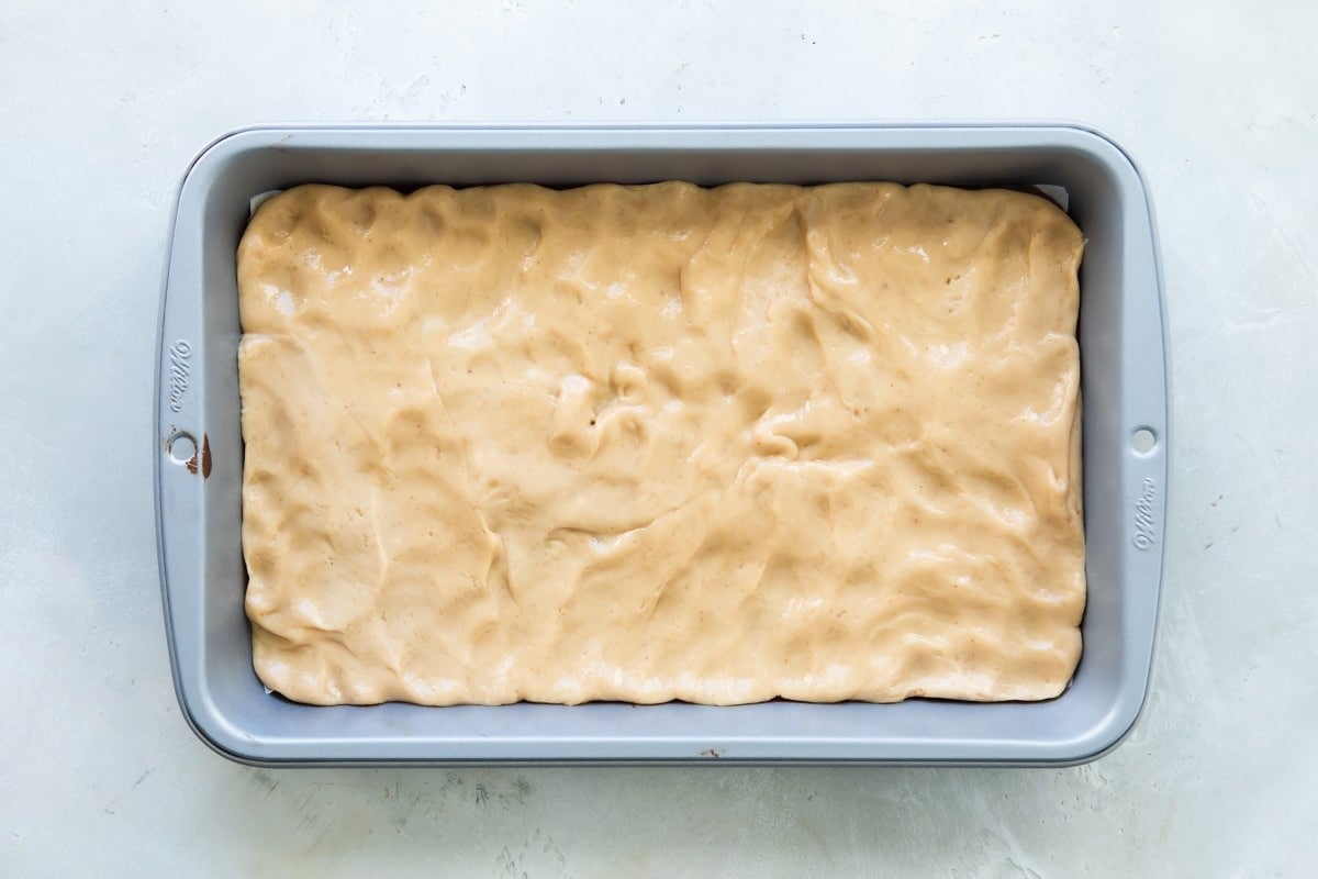A layer of of nougat spread out over hardened chocolate in a baking pan.
