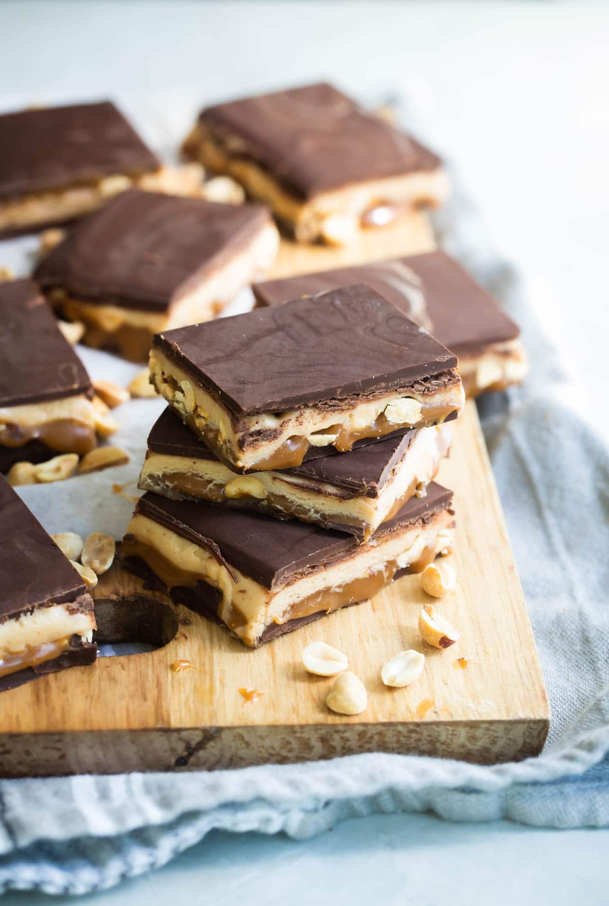 Homemade Snickers bars on a wooden cutting board.