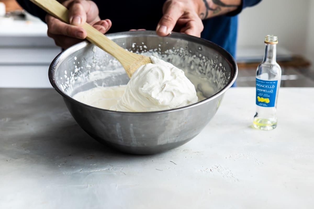 Limoncello cream being mixed in a silver mixing bowl.