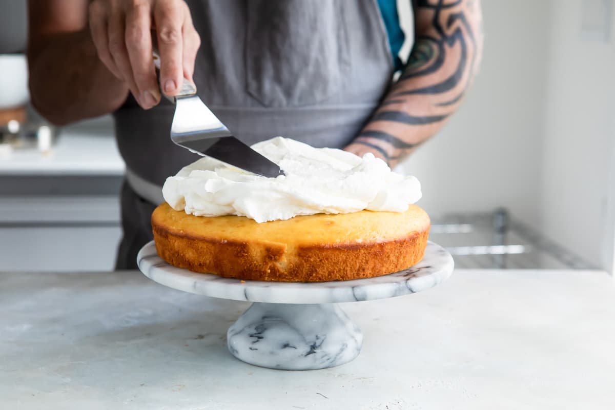 Lemon cake with limoncello cream on a marble cake stand.