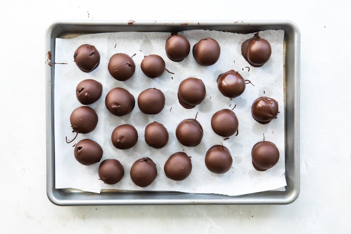 Oreo cookie balls on a parchment paper lined baking sheet.