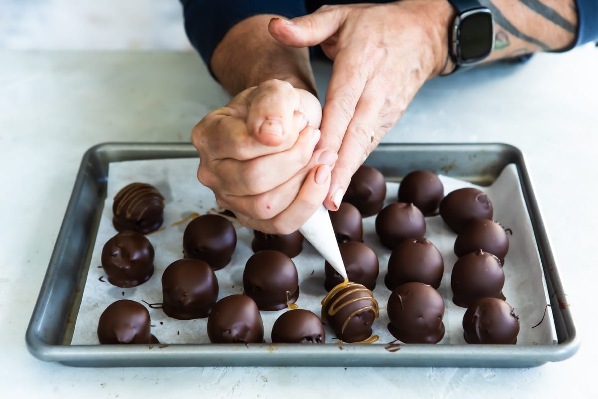 Someone drizzling caramel on Oreo cookie balls.