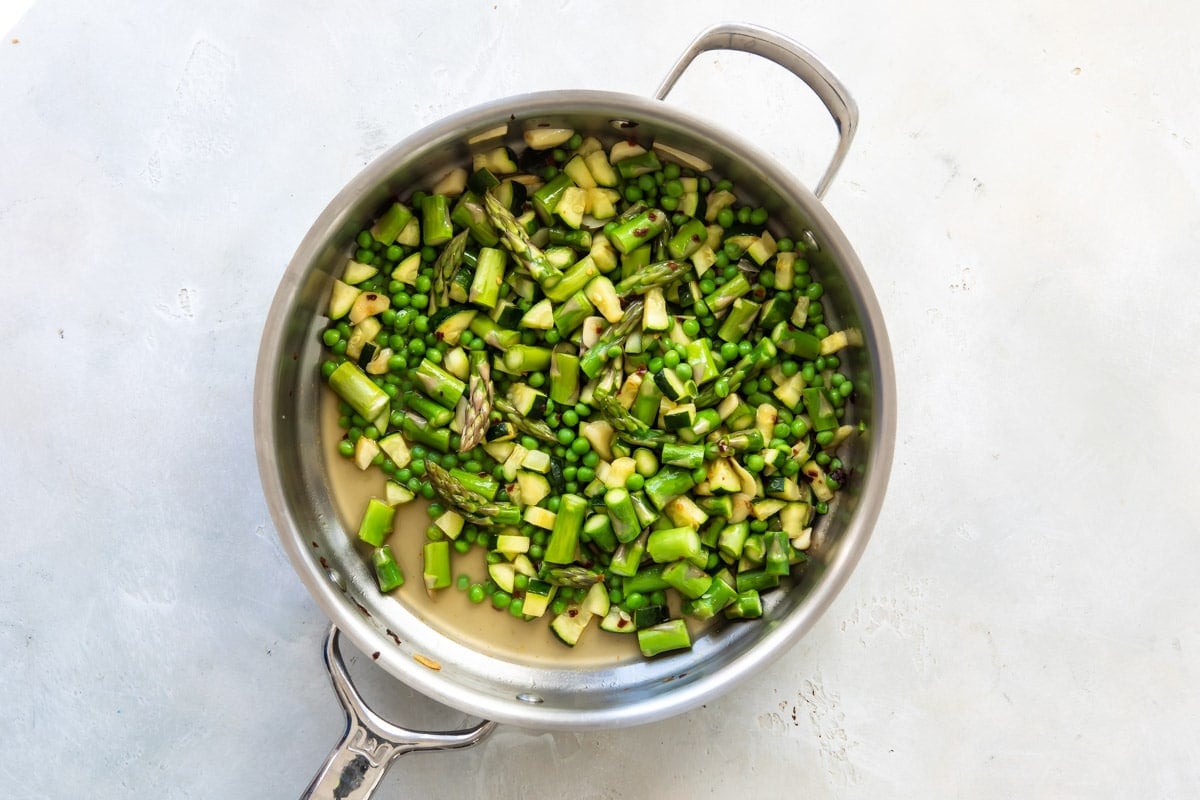 Zucchini and asparagus cooking in a skillet.