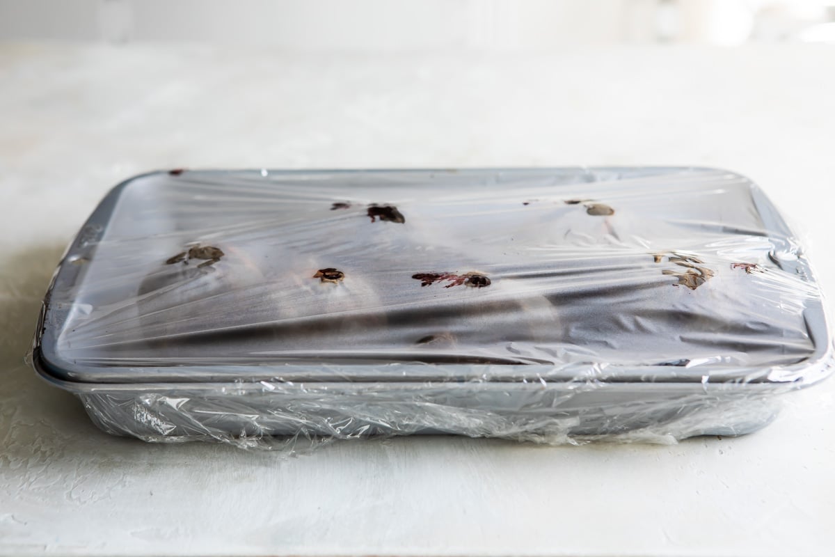 Beets in a pan covered in plastic wrap.