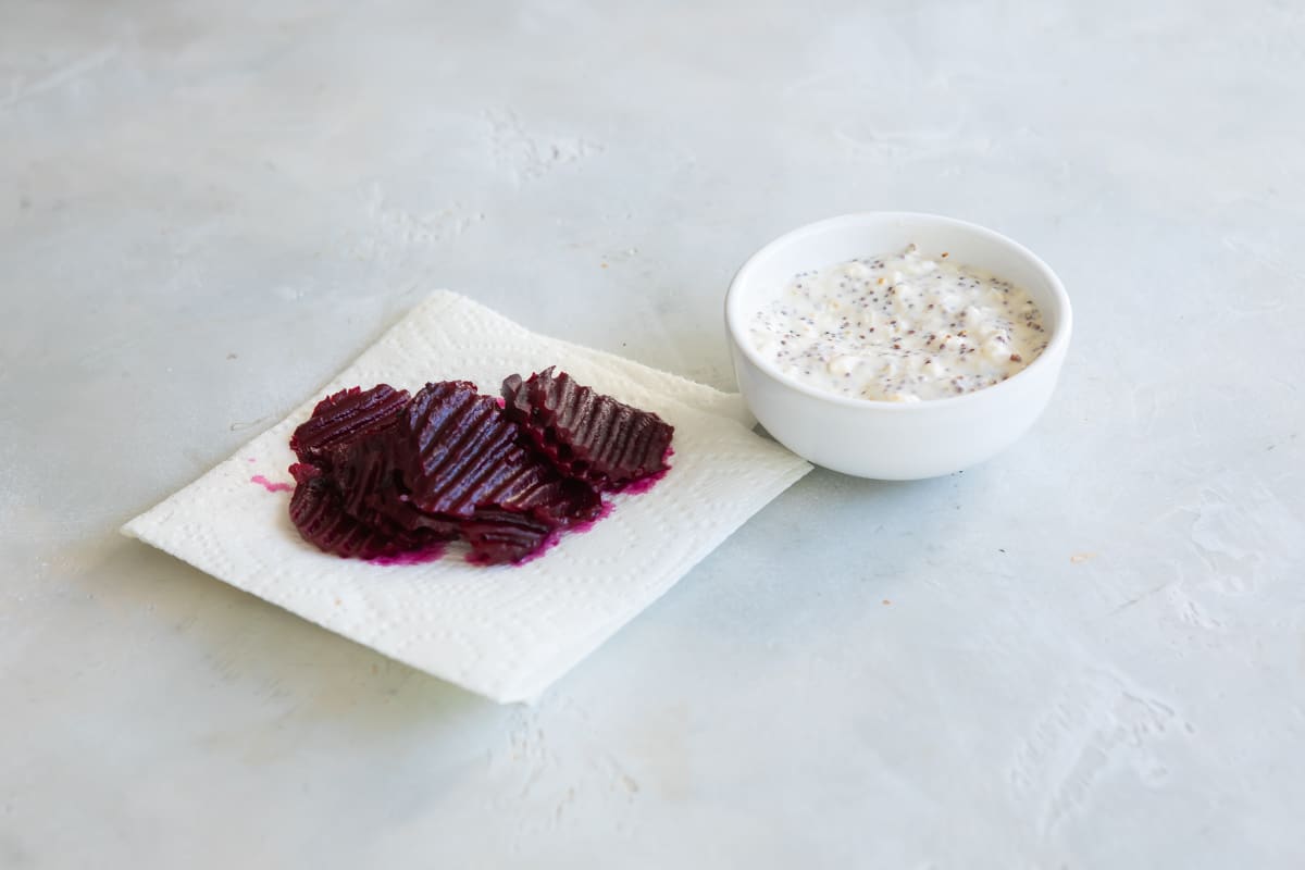 Pickled beets on a paper towel next to feta sauce.
