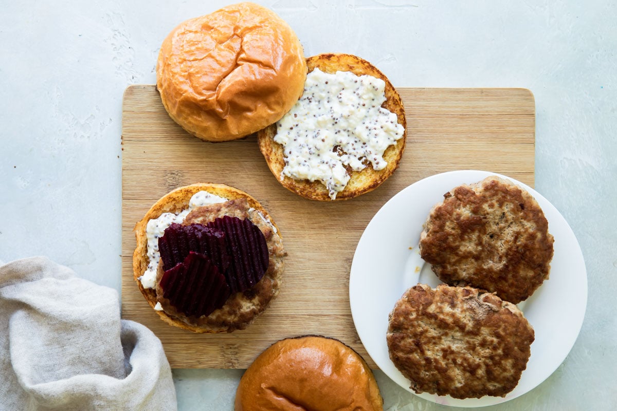 A disassembled pork burger on a wooden cutting board.