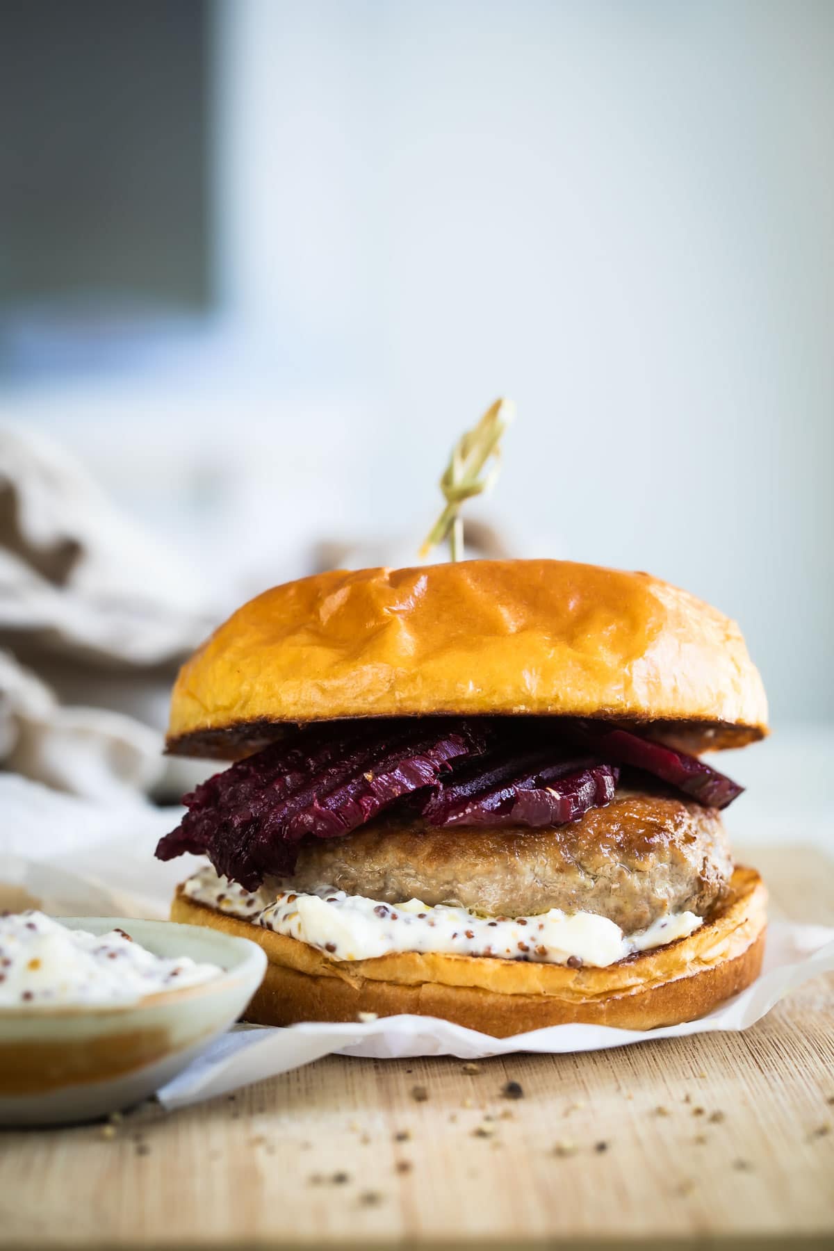 A pork burger on a wooden cutting board.