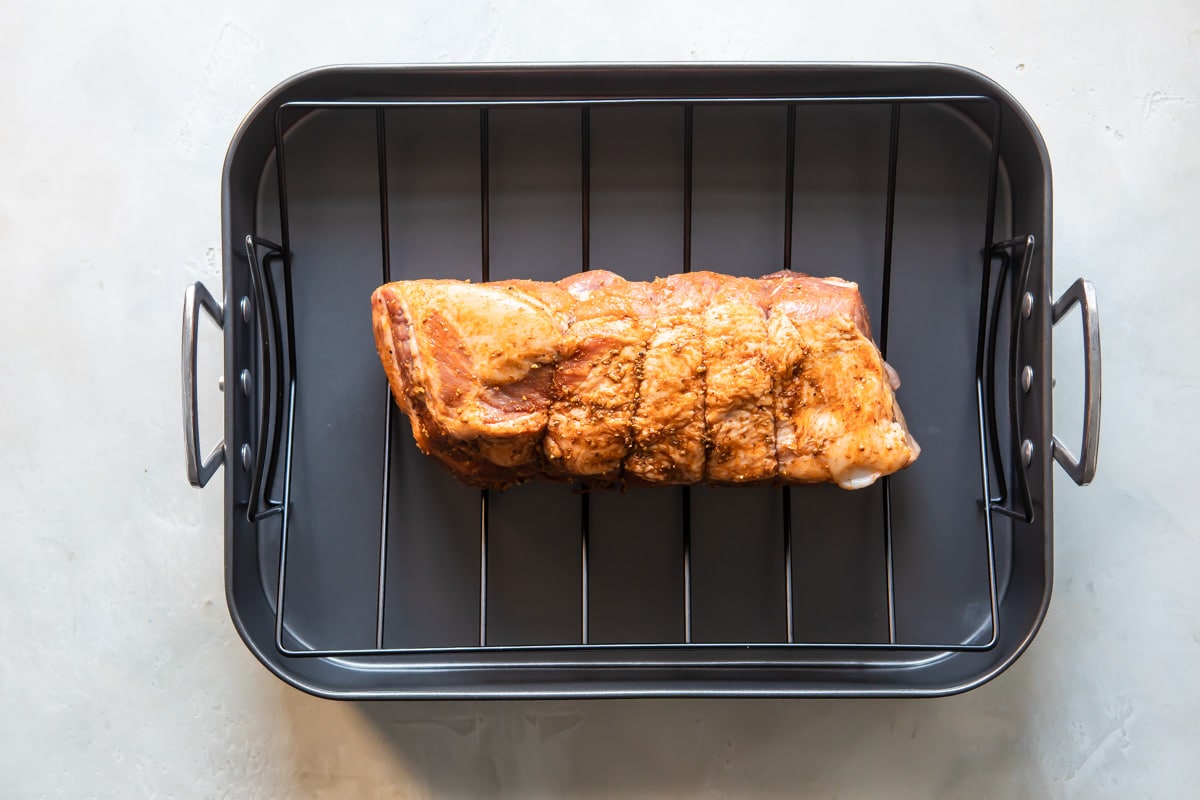 A pork roast in on a roasting rack before being cooked.