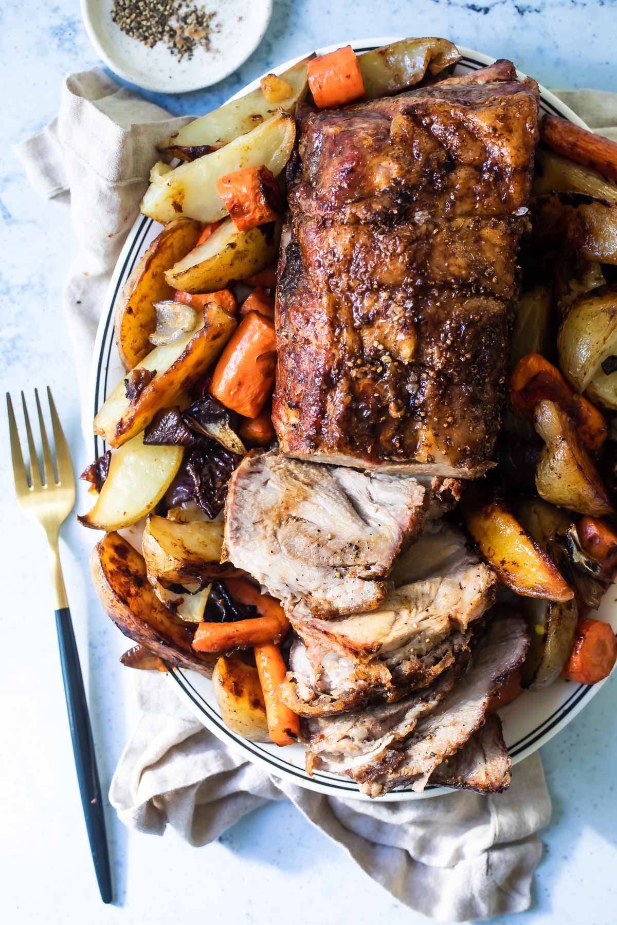 Pork roast on a plate with vegetables.