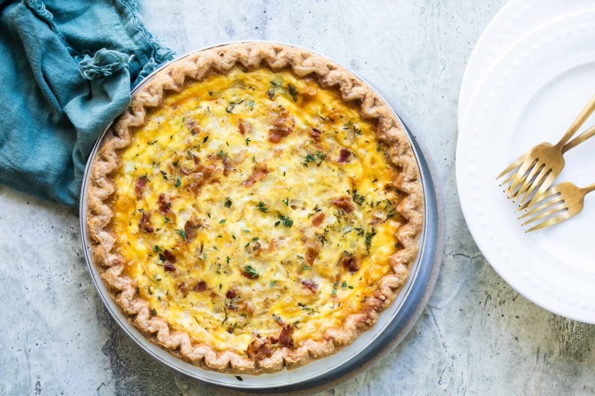 A quiche Lorraine in a pie pan on top of a round serving plate.