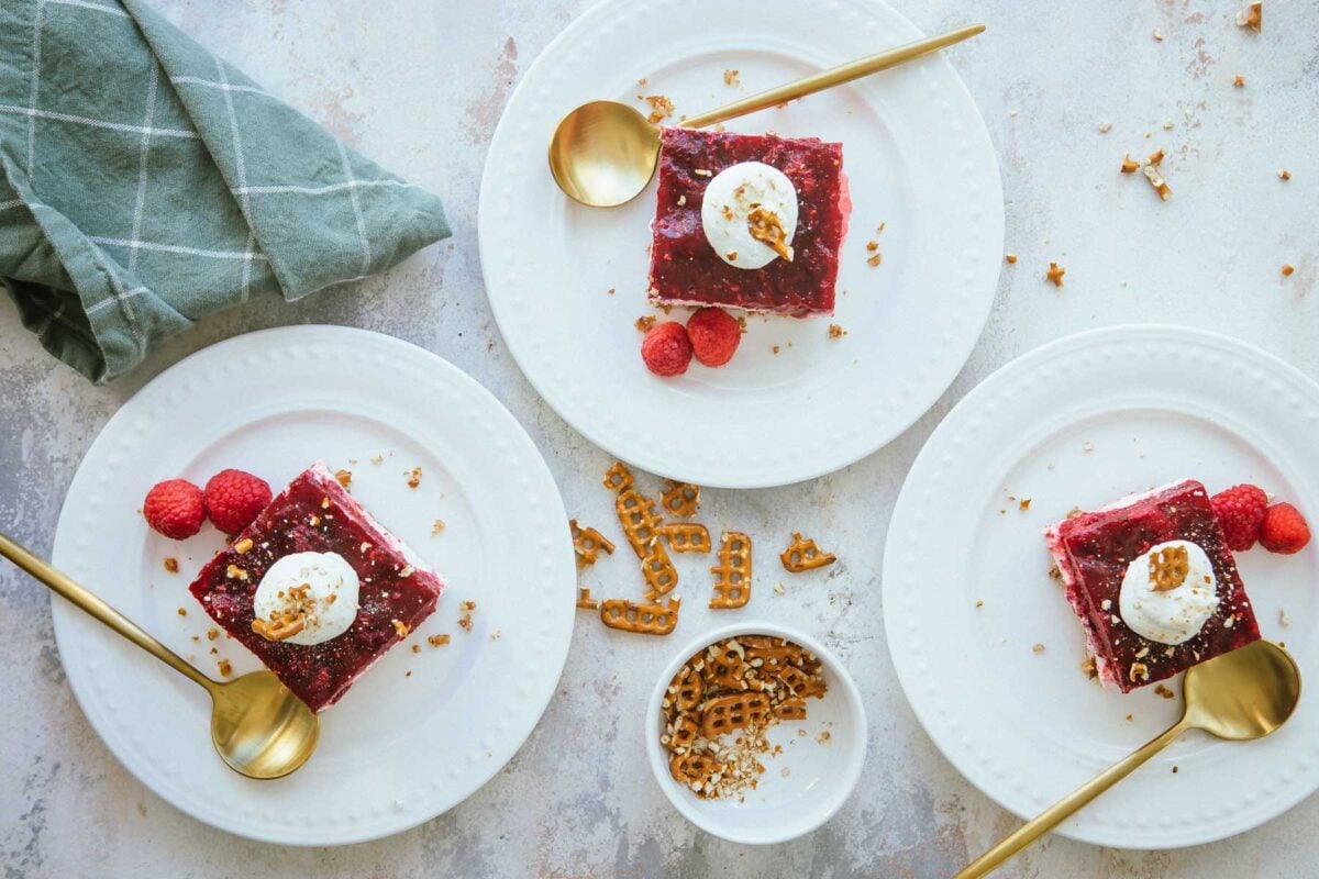 Raspberry pretzel jello salad slices on three plates.