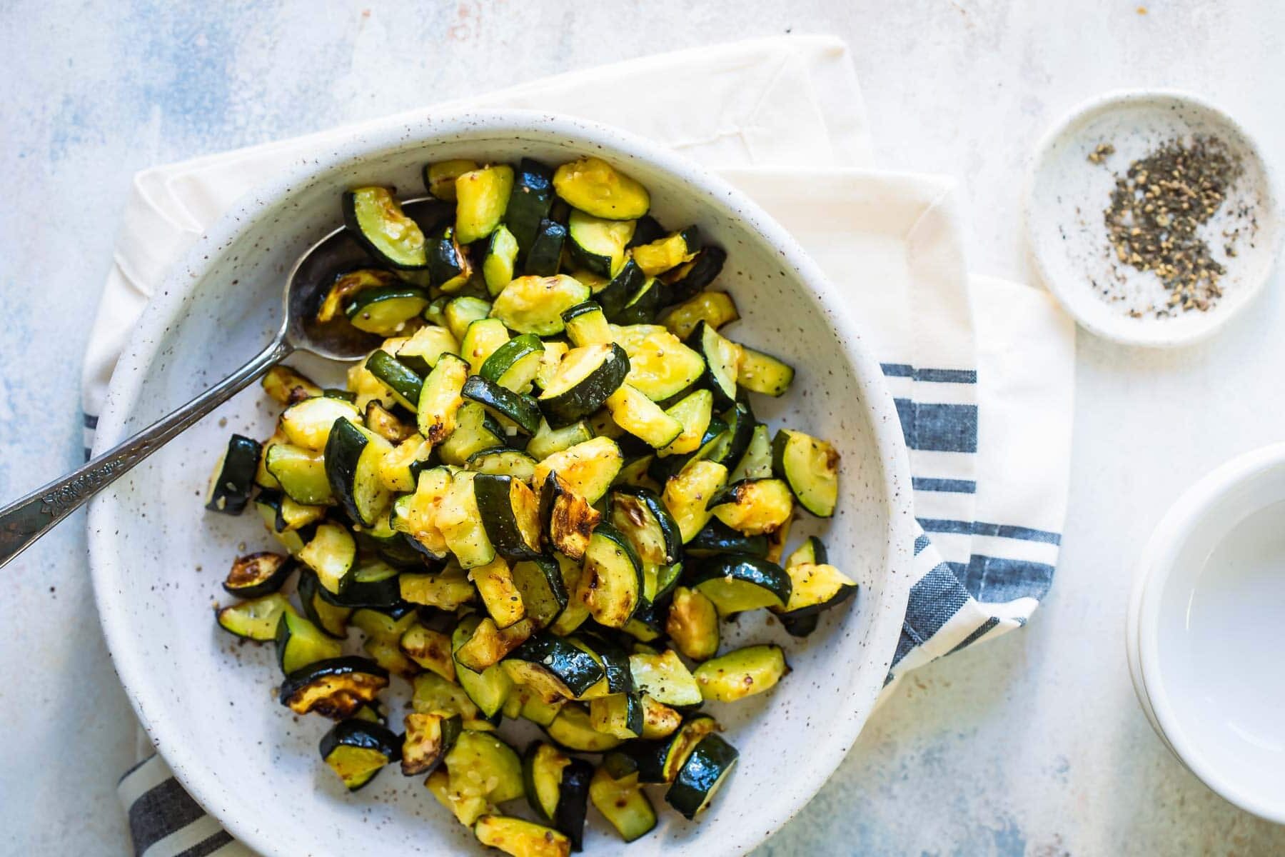 Roasted zucchini in a gray speckled bowl.
