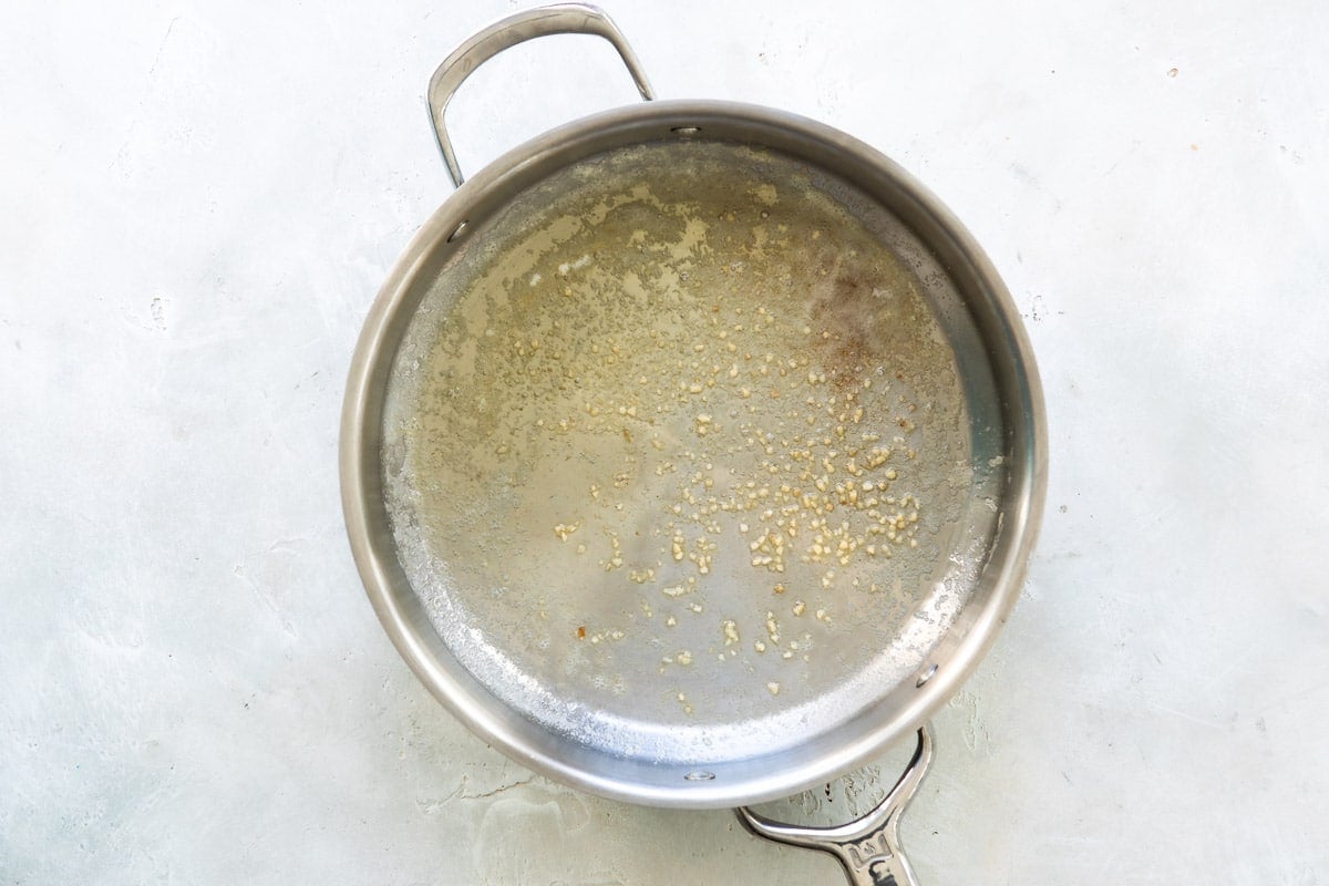 Garlic and oil in a silver skillet.