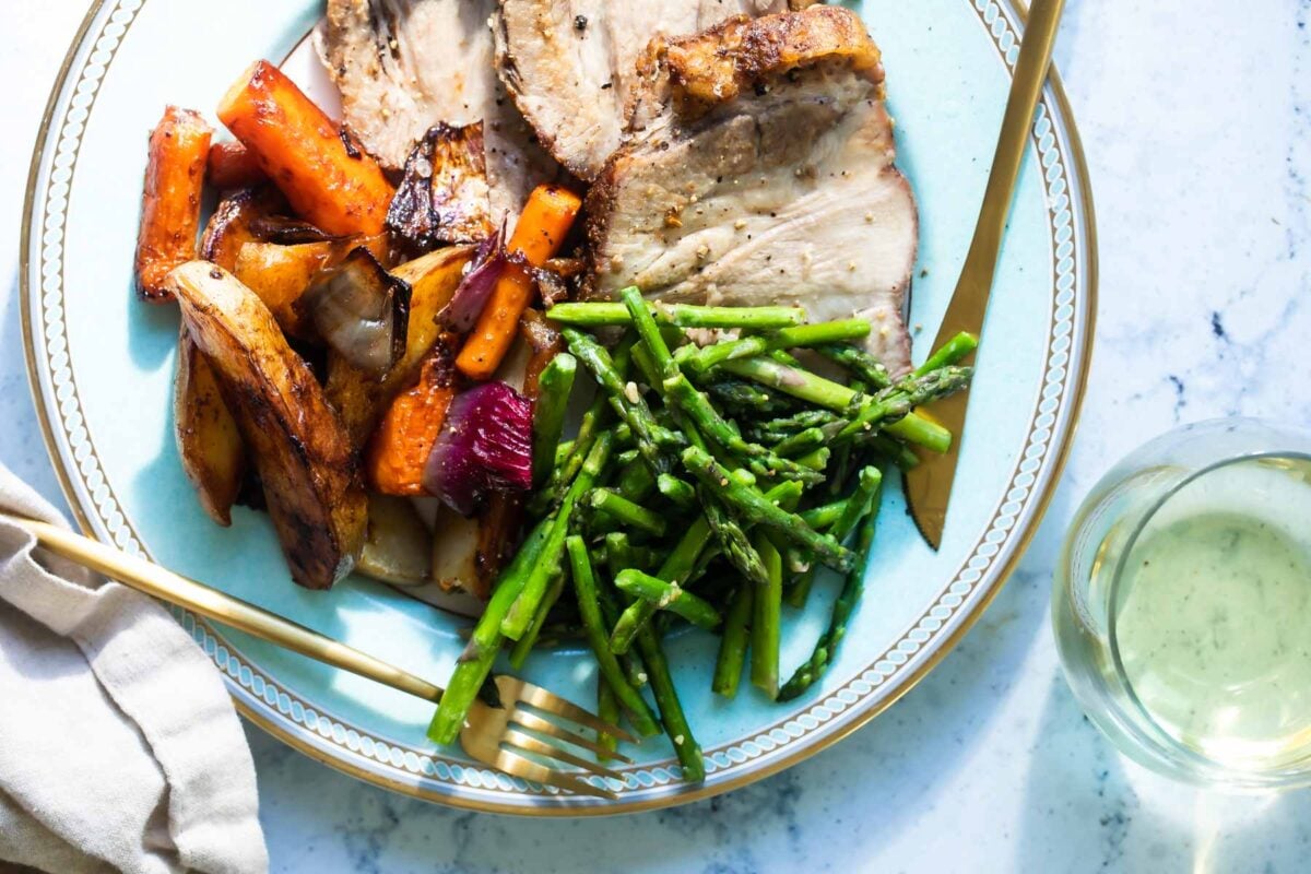 A light blue plate with asparagus, roast pork, and potatoes.