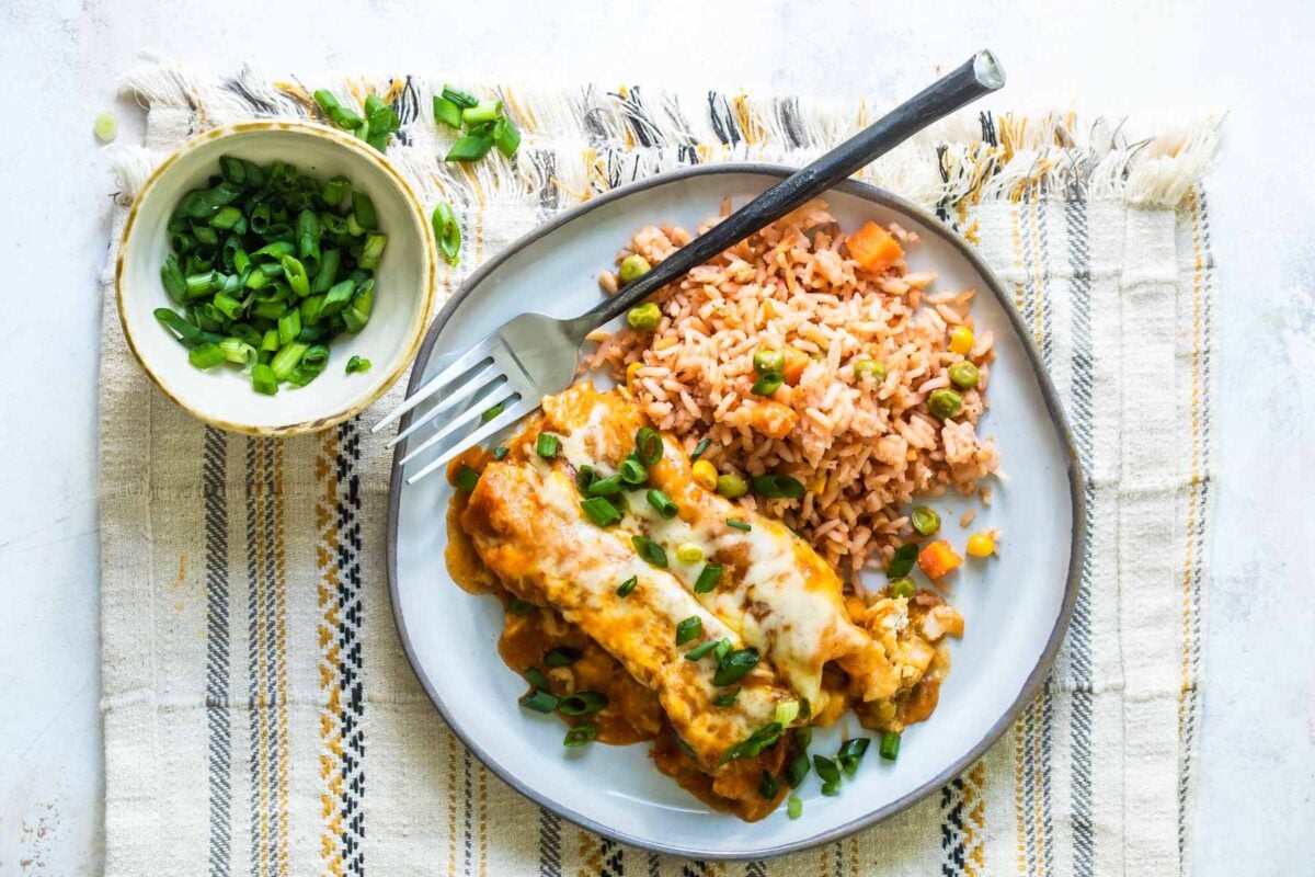 A plate with two enchiladas and Spanish rice.