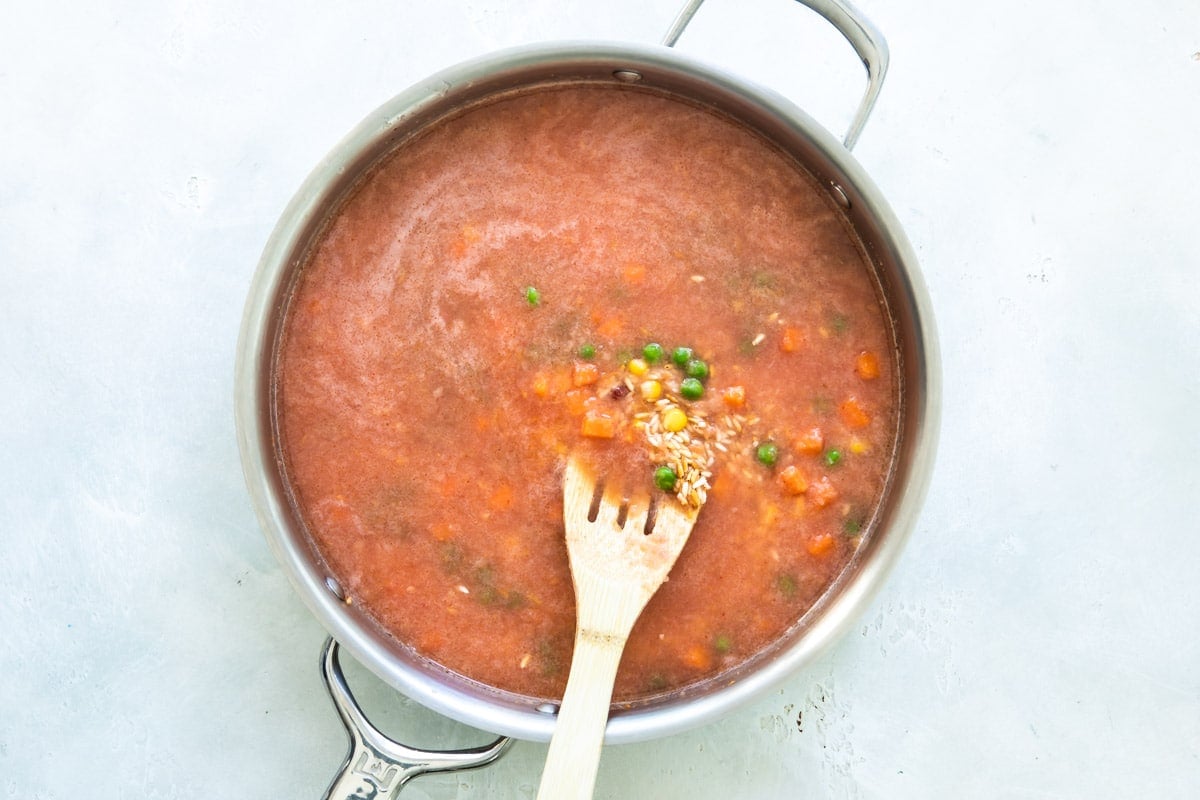 Spanish rice being cooked in a skillet before liquid is absorbed into the rice.