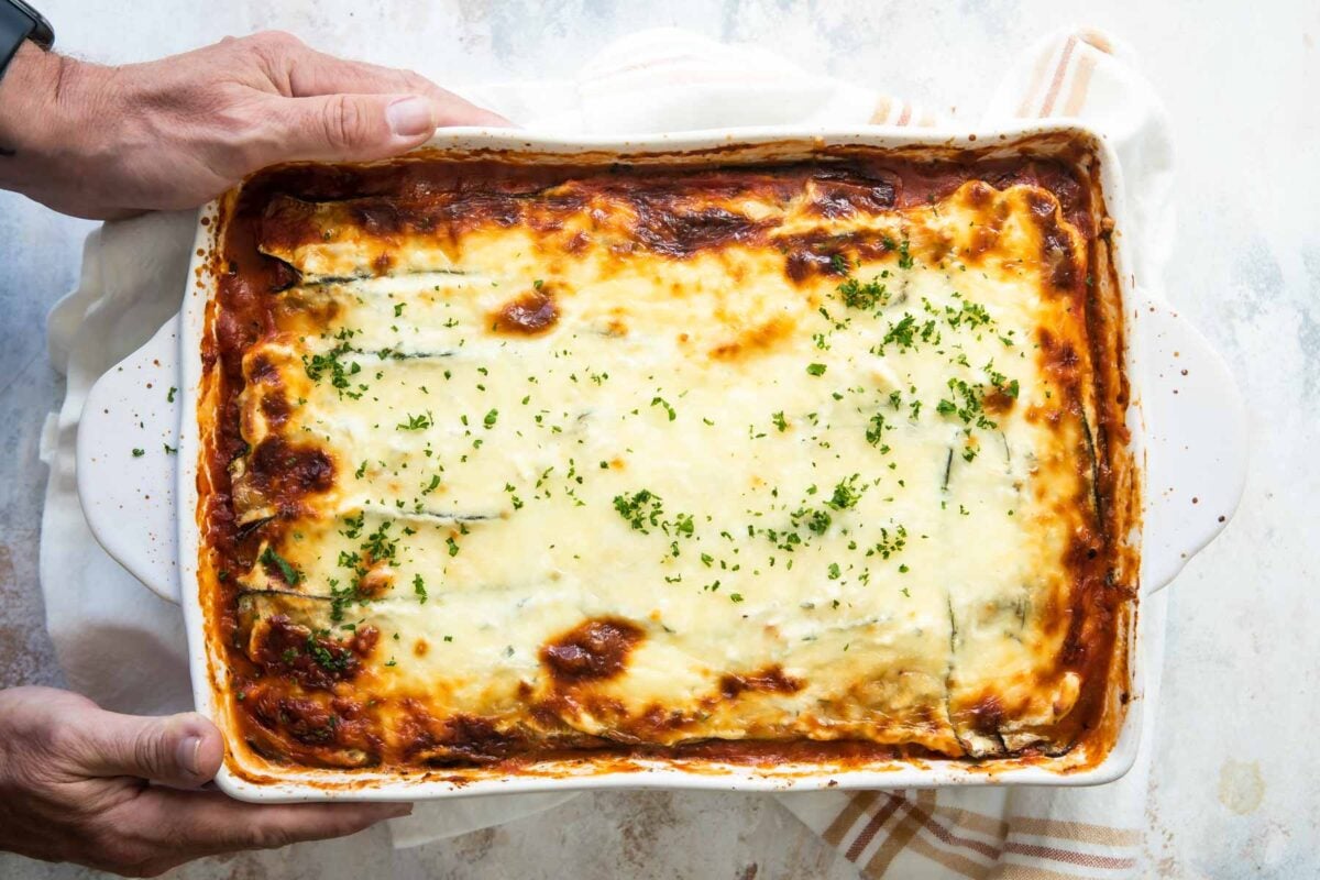Someone holding a baking dish of zucchini lasagna.