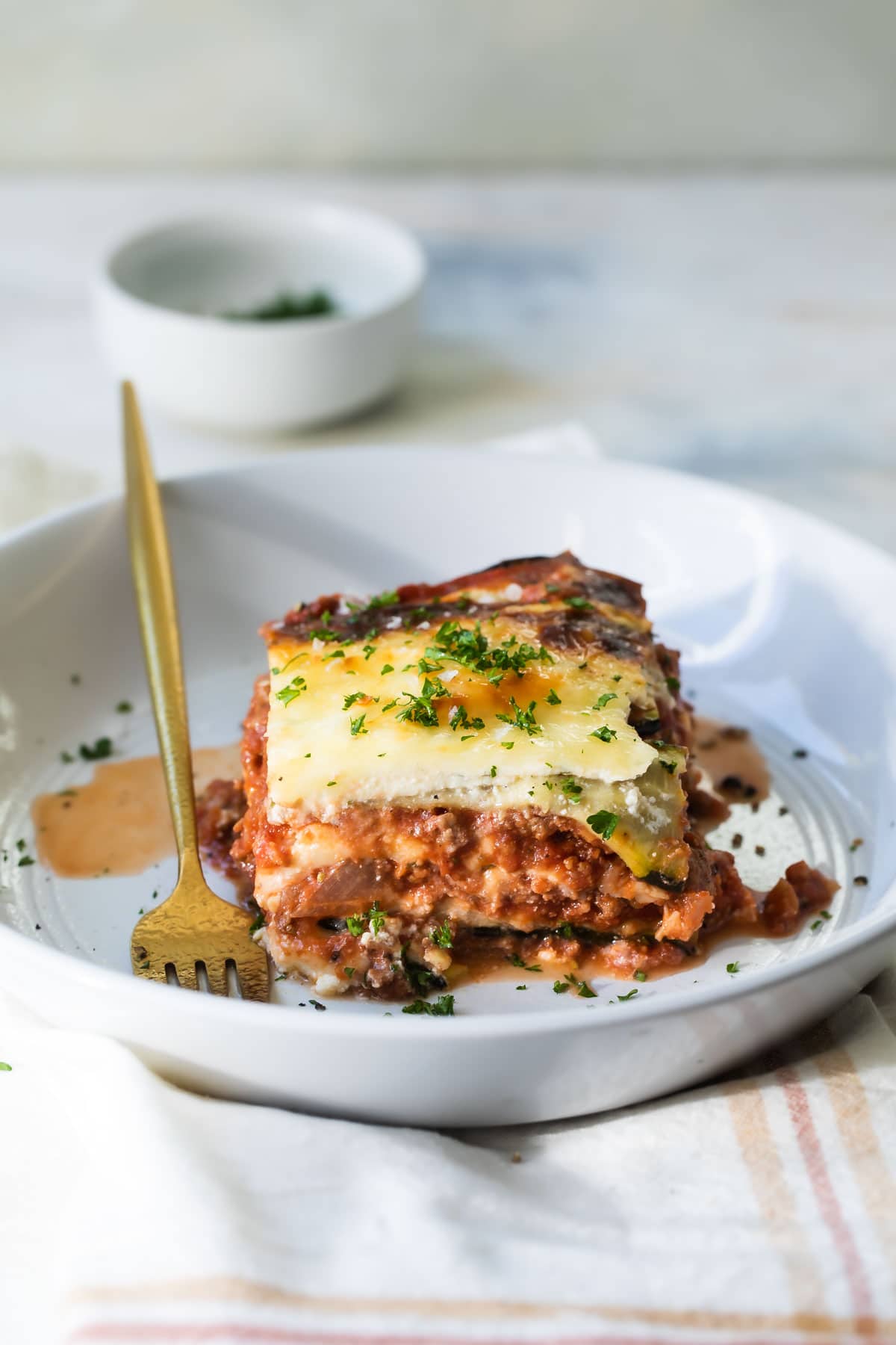 A slice of zucchini lasagna on a white plate.