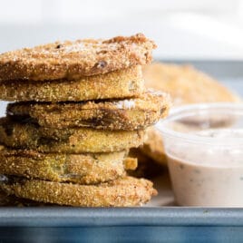 A stack of fried green tomatoes with a side of remoulade.