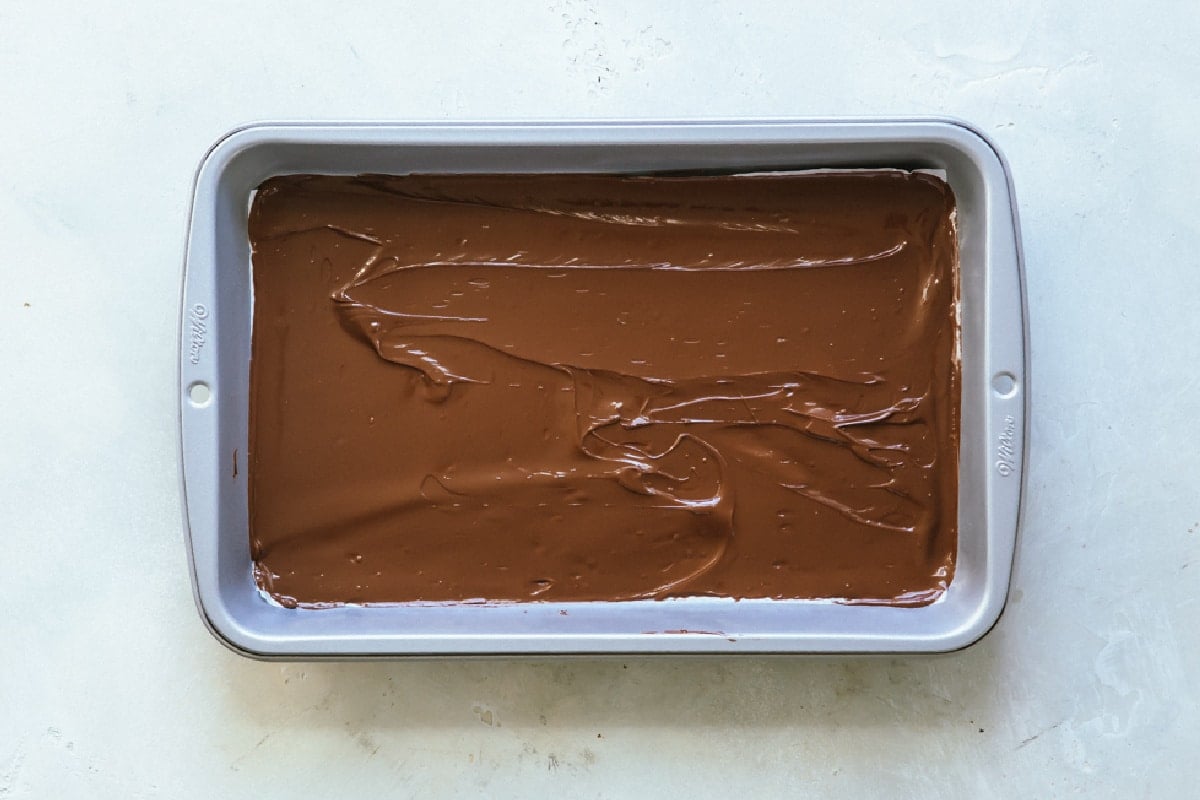 A layer of chocolate spread out in a baking pan.